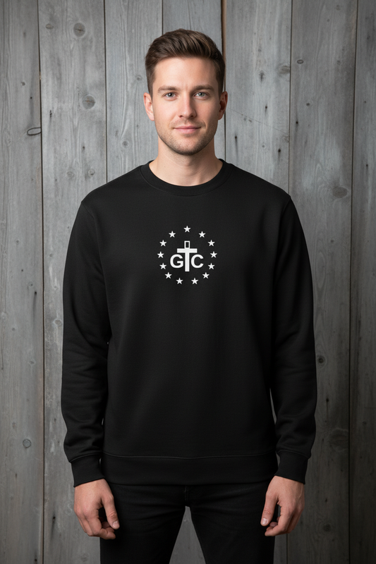 Male model wearing black G&C crewneck with relaxed fit against rustic wood